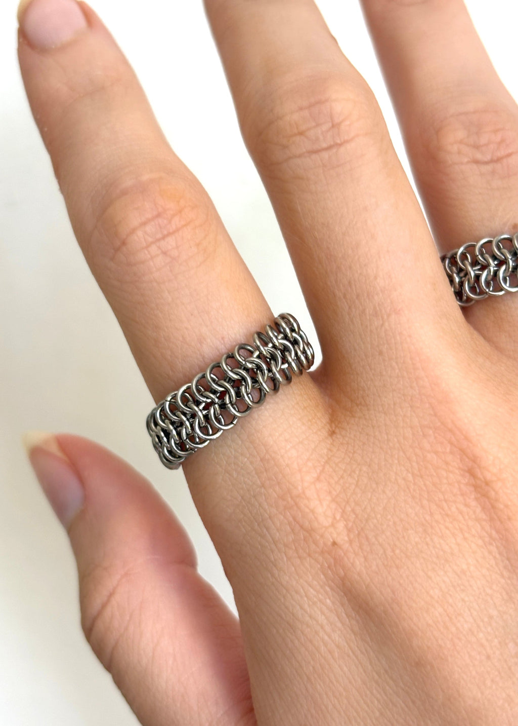Silver chain ring on a finger against a white background