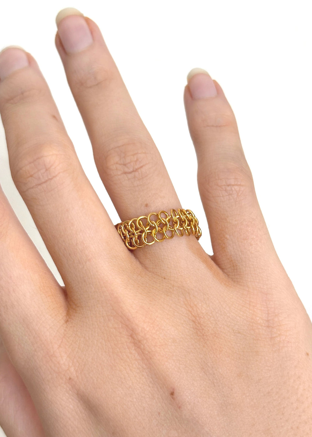 Gold chain ring on a hand against a white background