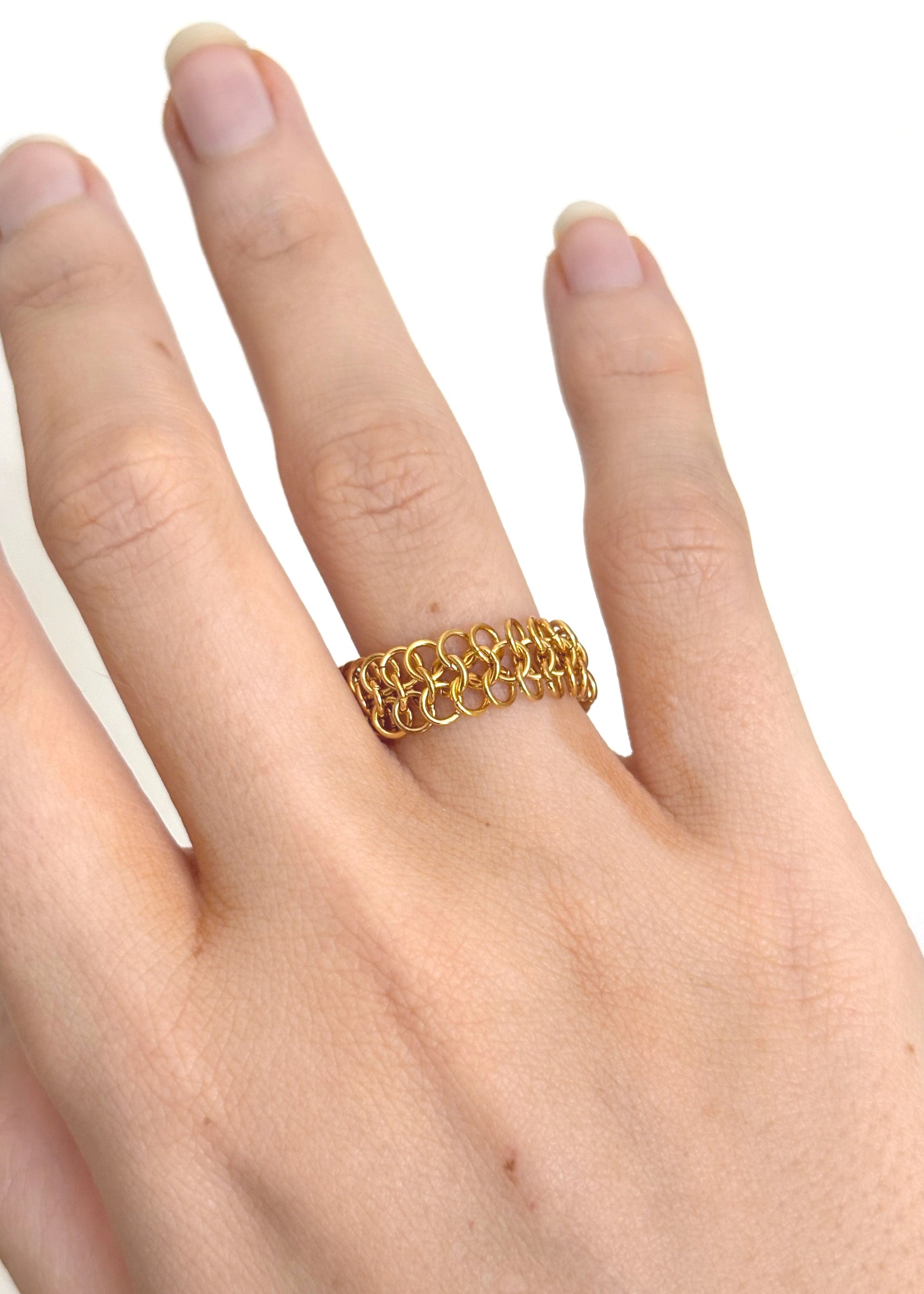 Gold chain ring on a hand against a white background
