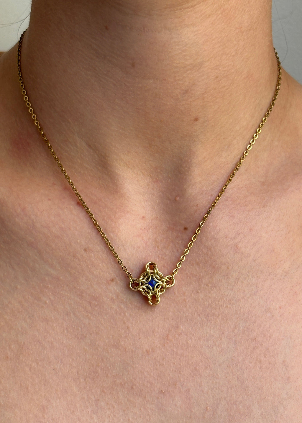 Gold necklace with a star-shaped pendant worn by a person