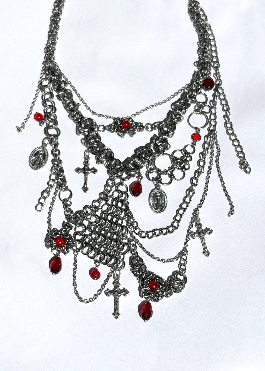 Elaborate necklace with chains, charms, and red stones on a white background
